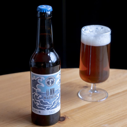Bottle and glass of beer on a wooden surface with a black background