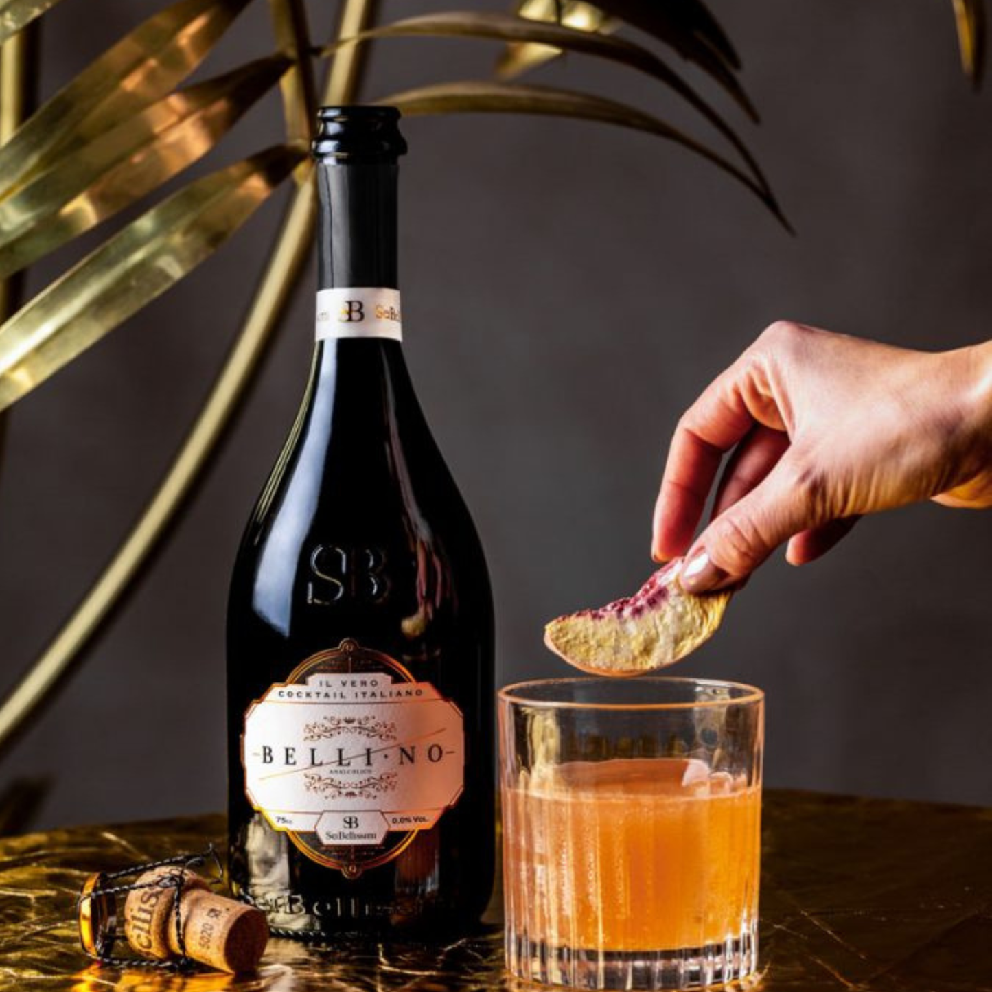 Bottle of Bellino wine with a glass of orange juice and a hand holding a cracker.