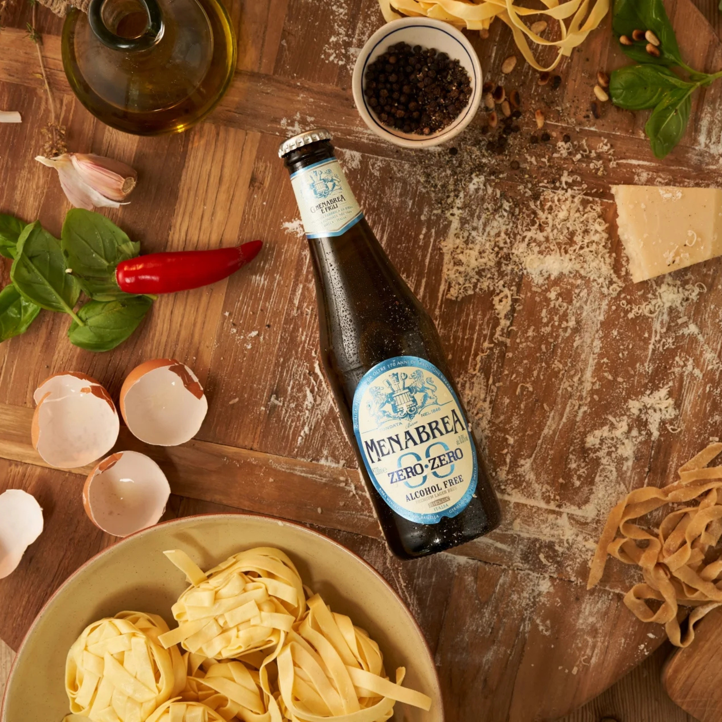 Bottle of Menabrea beer on a wooden table with pasta and ingredients