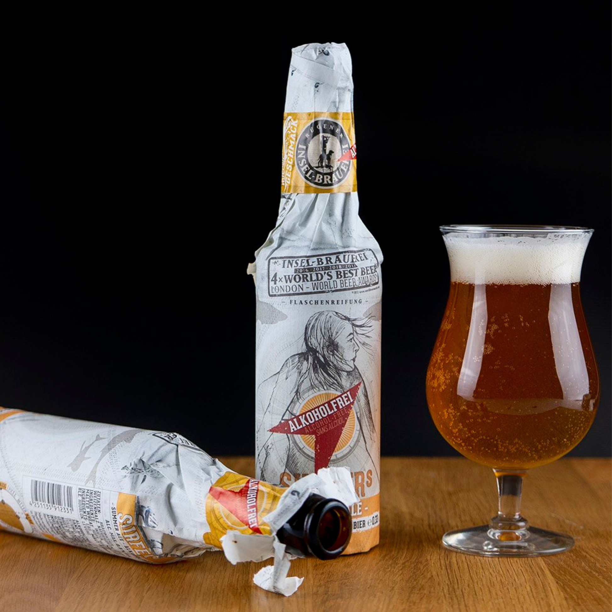 Alcohol-free beer bottle and glass on a wooden surface with a black background