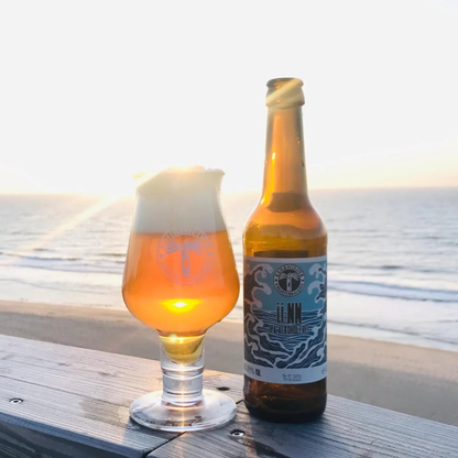 Beer bottle and glass on a wooden surface with a beach background