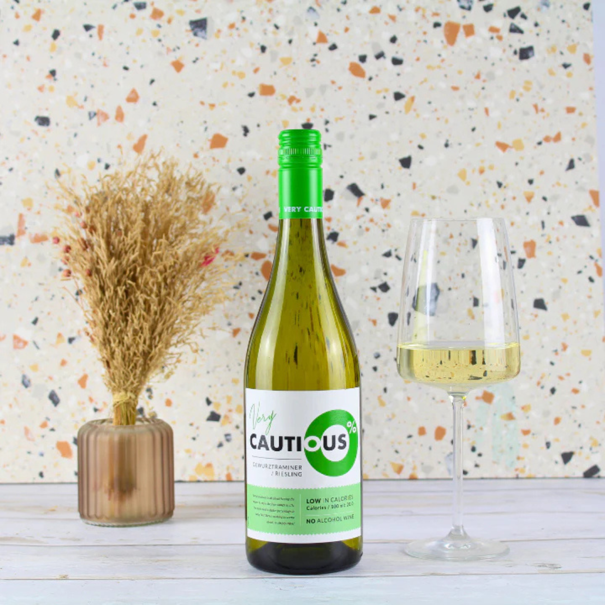 Bottle of 'Lively Cautious' white wine with a glass on a textured surface