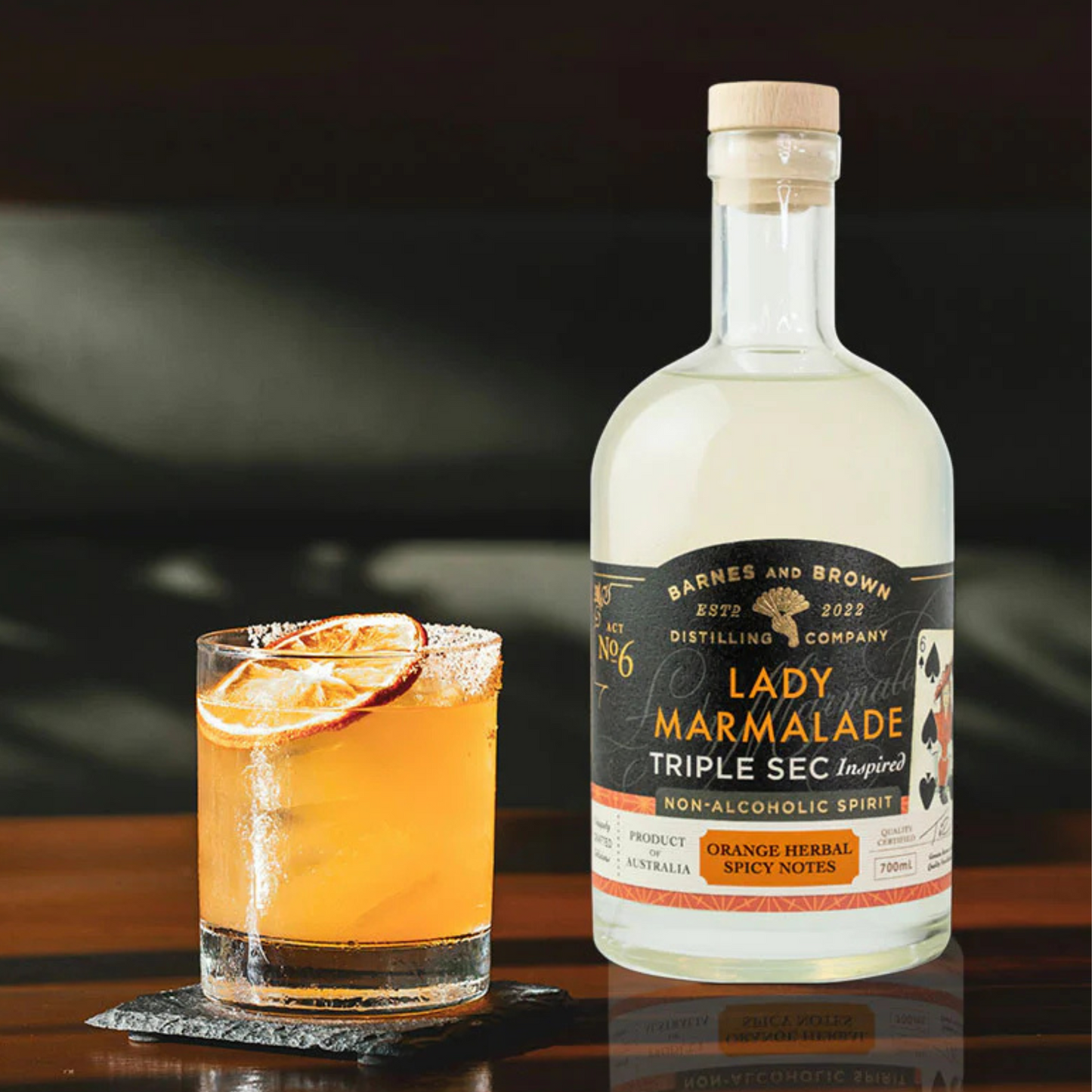 Bottle of Barnes & Brown Distilling Co. Lady Marmalade Triple Sec with a cocktail on a dark background