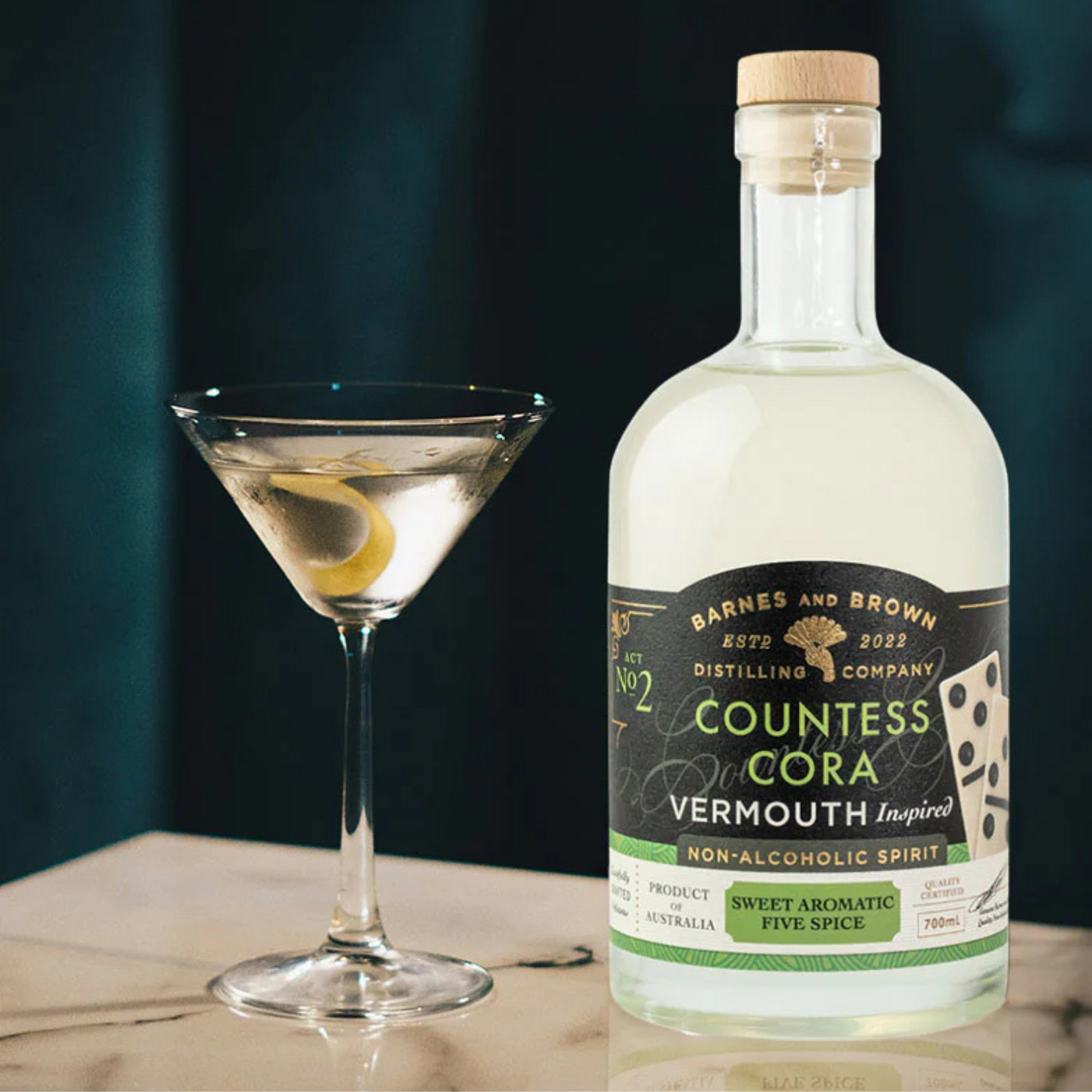 Bottle of Countess Cora Vermouth Inspired non-alcoholic spirit with a cocktail glass on a wooden surface.