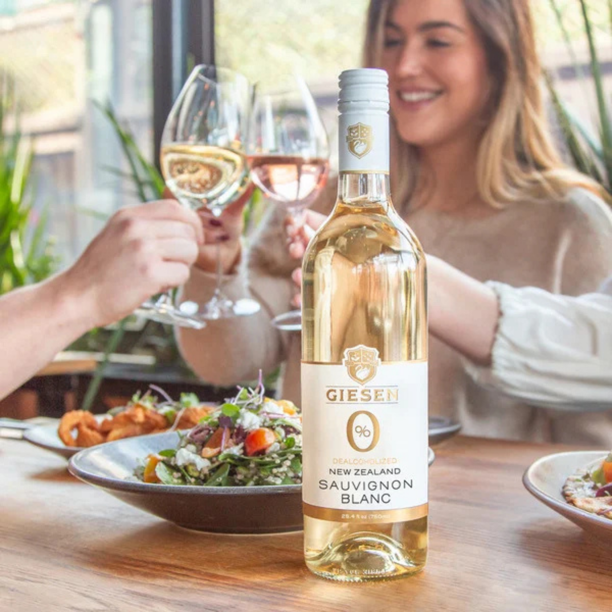 Bottle of Gieser Sauvignon Blanc 0% with people enjoying a meal in the background