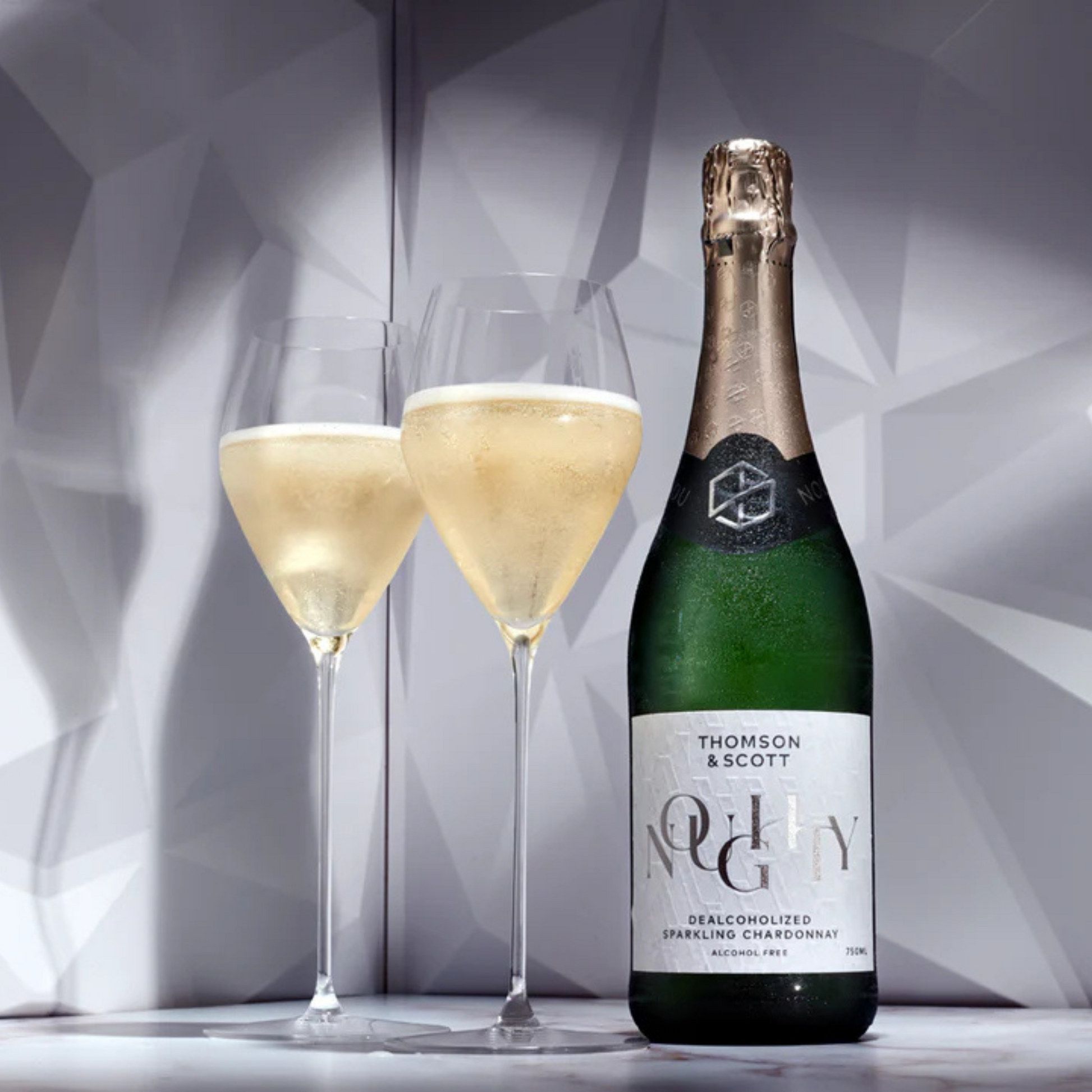 Bottle of Thomson & Scott NV Chardonnay with two glasses of champagne on a geometric background