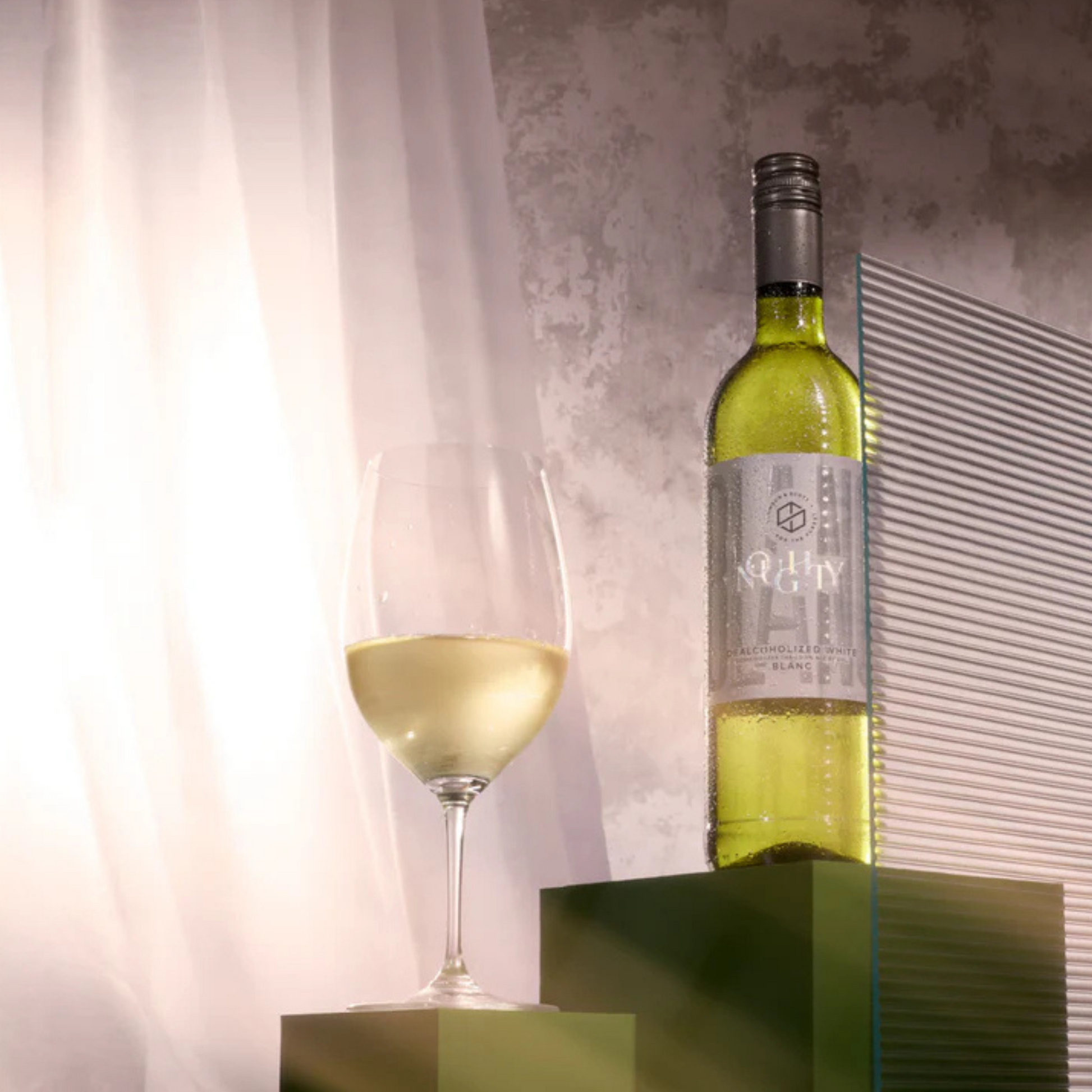 Bottle of white wine with a glass on a reflective surface