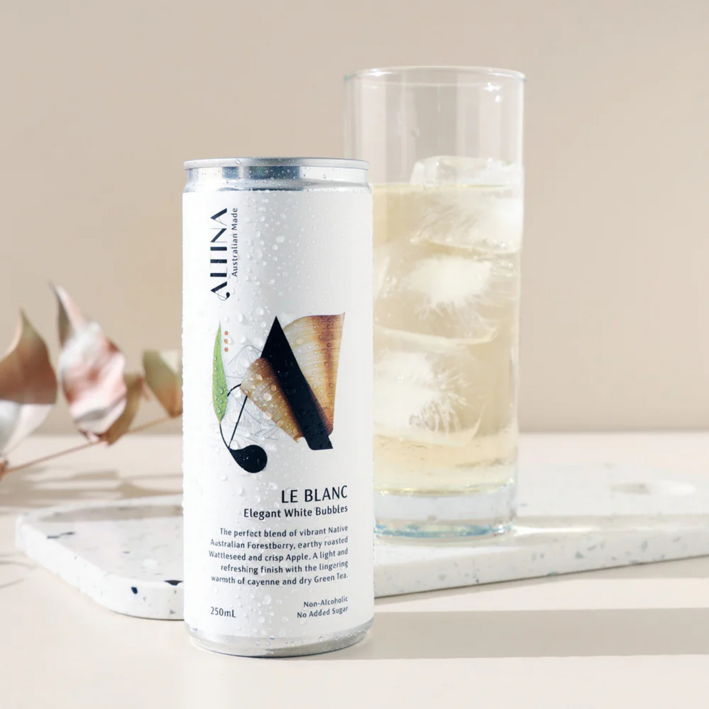 Can of 'Le Blanc' sparkling white wine next to a glass filled with the same wine on a marble surface.