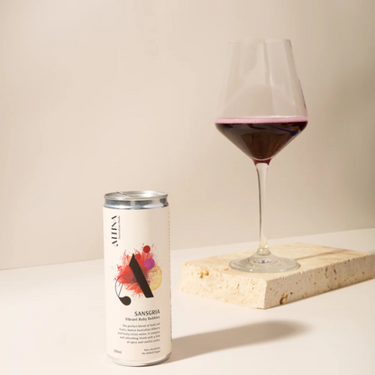 Can of Altina Sangria next to a glass of red wine on a light surface with a neutral background