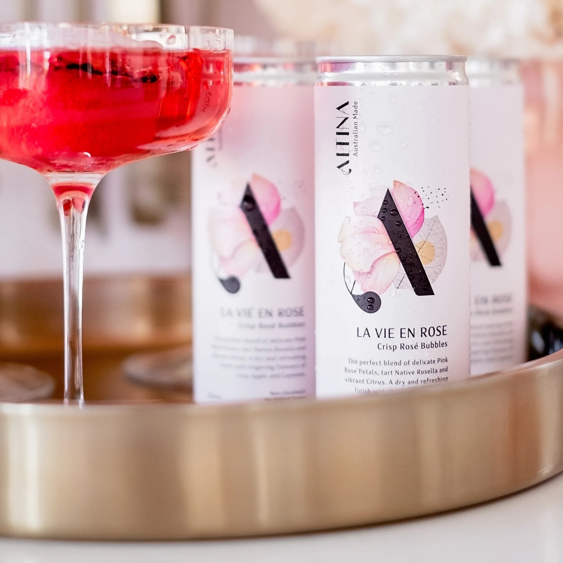 Cans of 'La Vie en Rose' sparkling rose wine with a cocktail in the foreground.