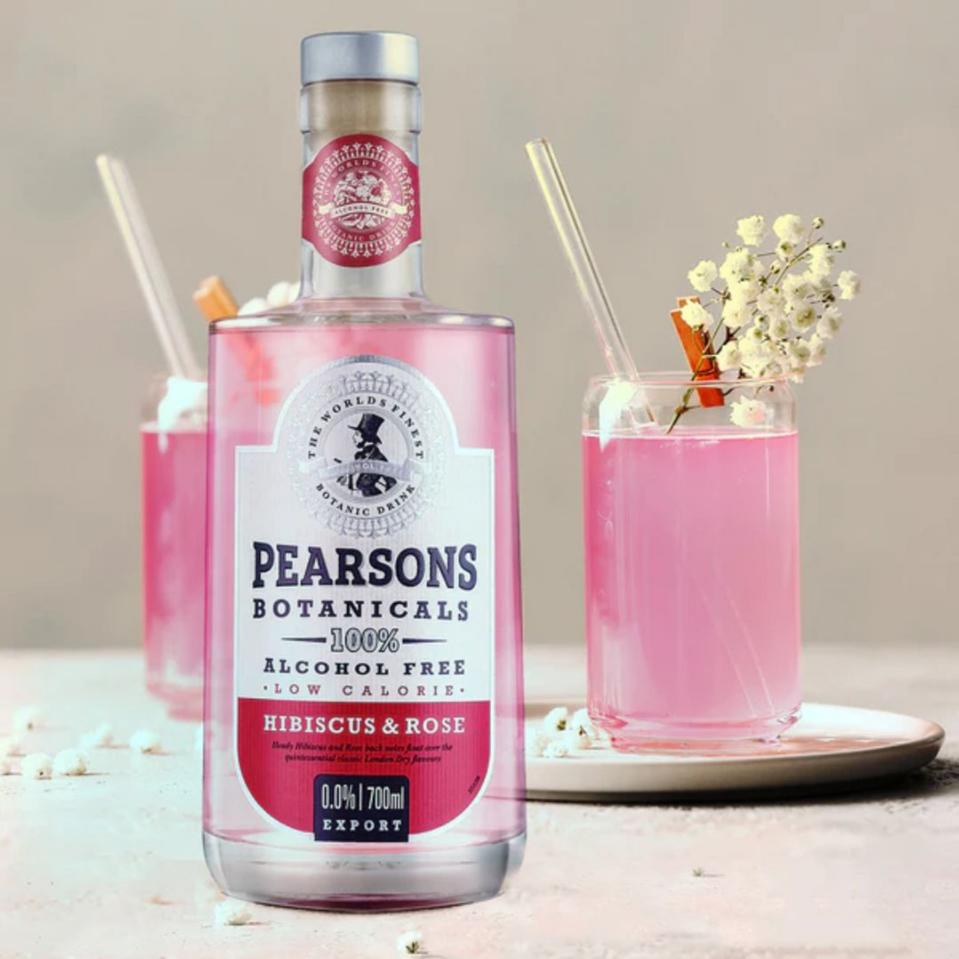 Pink bottle of Pearsons Botanicals with two glasses of pink drink on a neutral background
