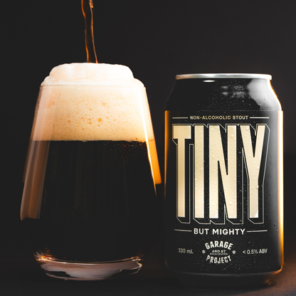 Can of 'Tiny But Mighty' non-alcoholic stout with a glass of the beer on a dark background