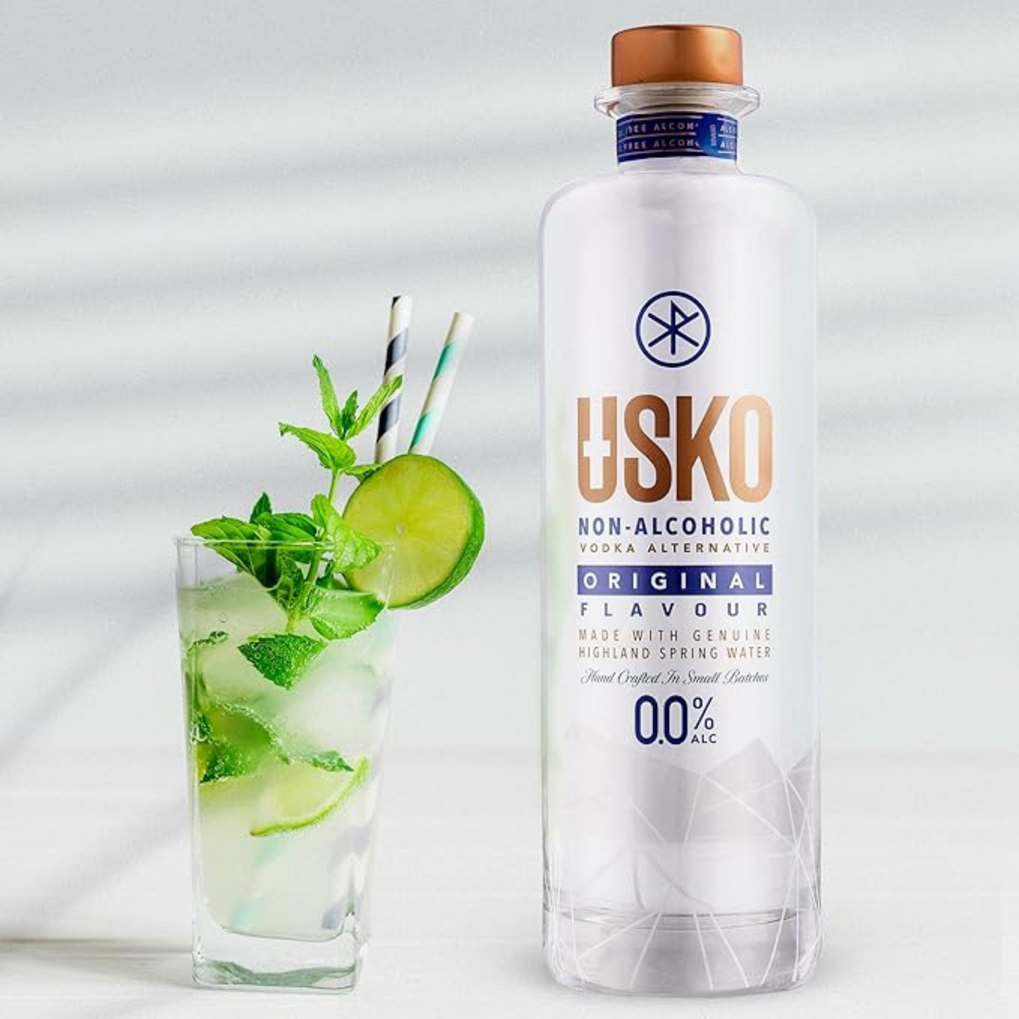 USKO non-alcoholic vodka alternative bottle with a glass of lime and mint cocktail on a light background